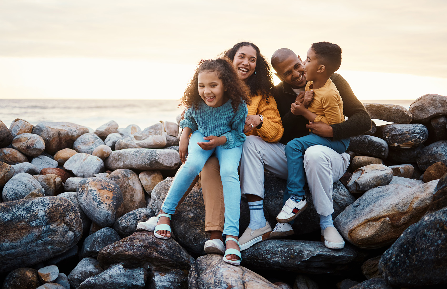 Four people sitting on rocks near the sea.
